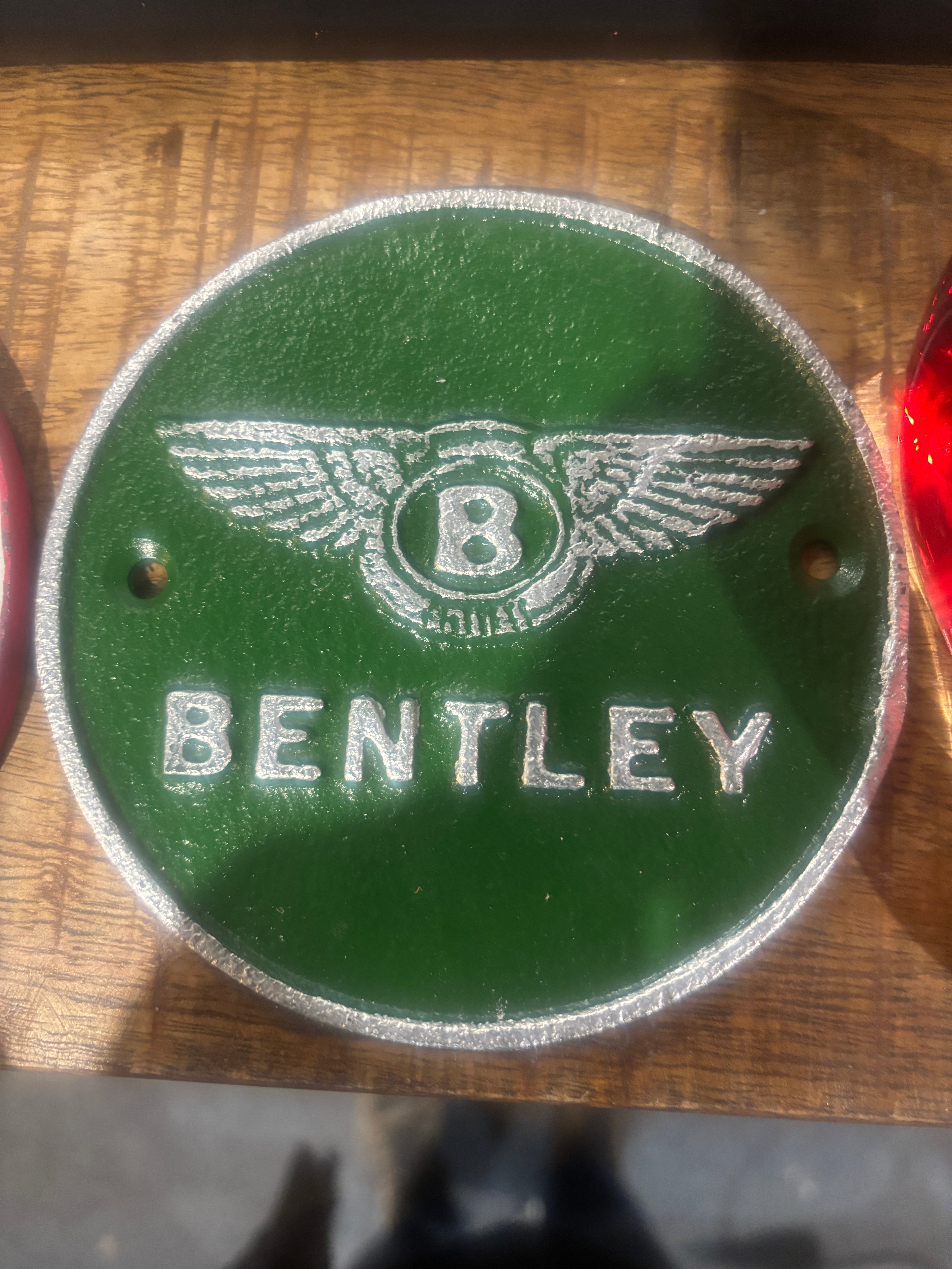 Bentley logo on a green background cast metal plaque on a wooden background