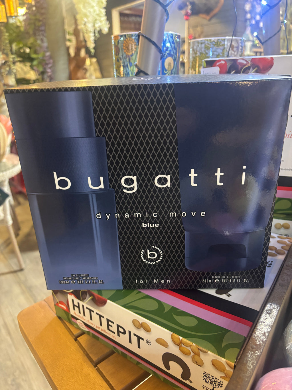 Bugatti perfume packaging on a surface with various items in the background