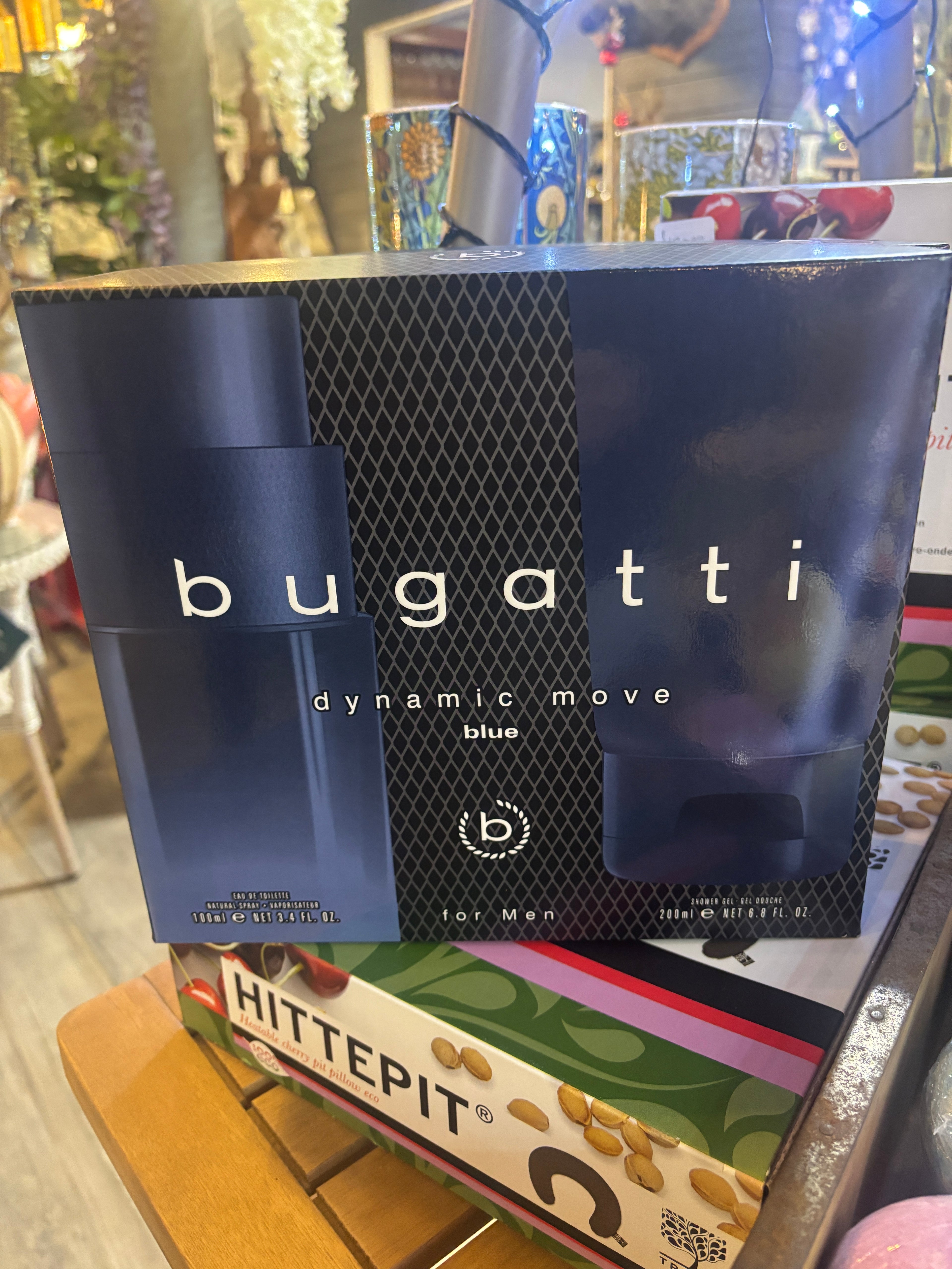 Bugatti perfume packaging on a surface with various items in the background