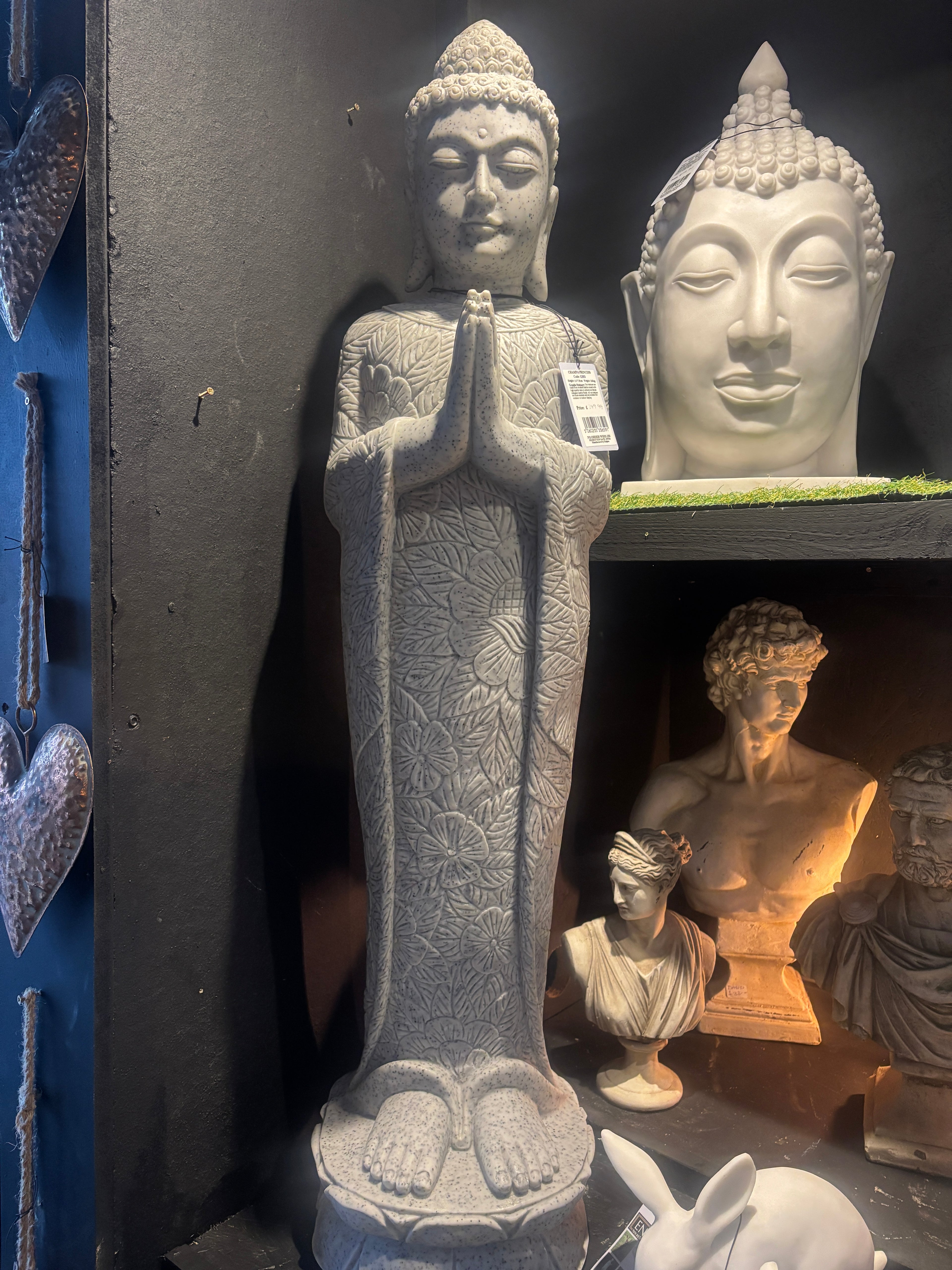 Stone Buddha statue on a black surface with other statues in the background