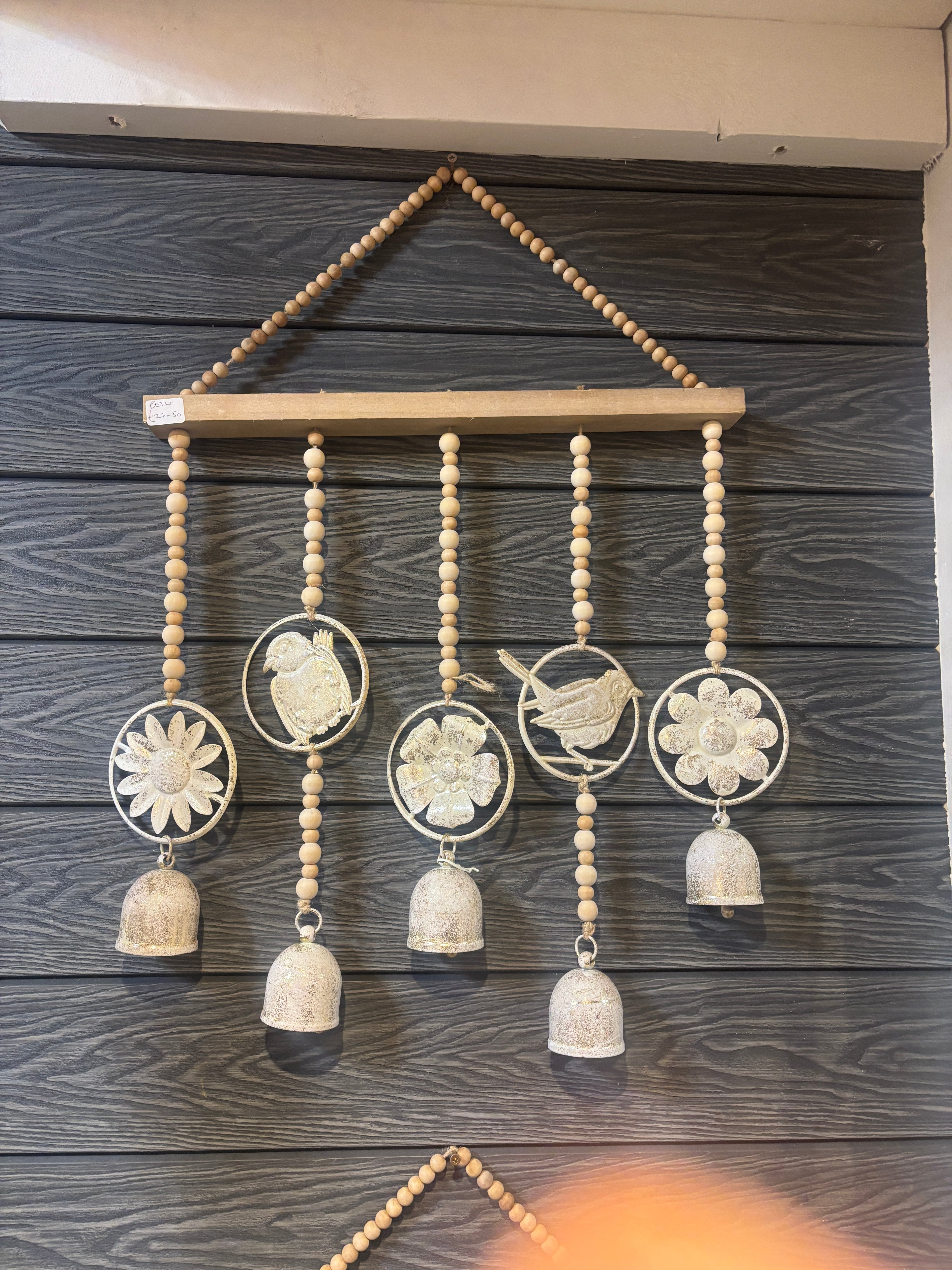 Decorative wall hanging with beads and circular cutouts on a wooden panel.