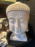 White Buddha head sculpture with a visible tag on a dark surface