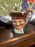 Decorative miniature royal doulton toby jug ceramic piece with a face on a wooden surface