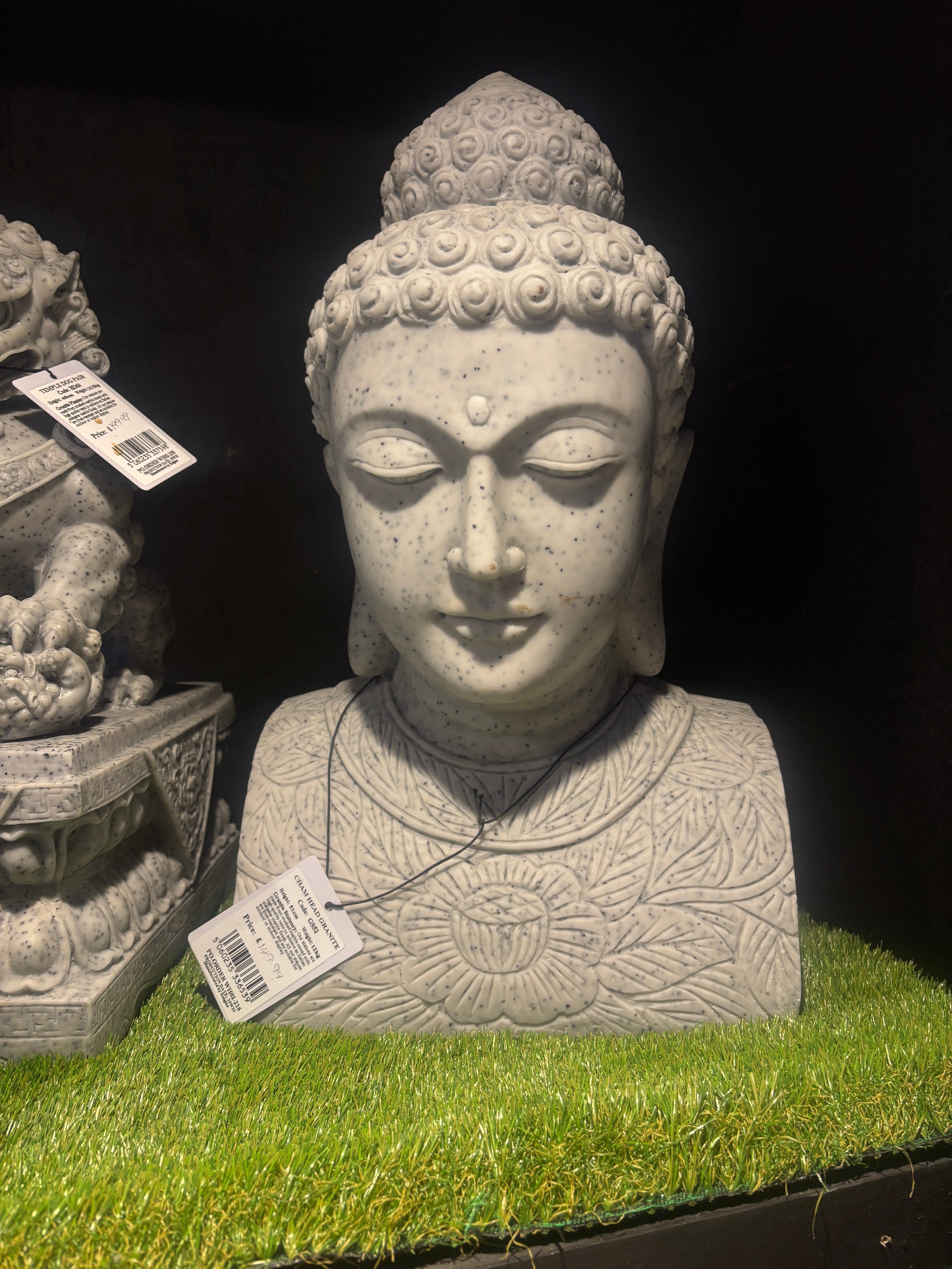 Stone Buddha statue with a tag on a grassy background