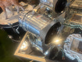 Metallic engine or mechanical component studio style spotlight on a reflective surface with decorative items in the background