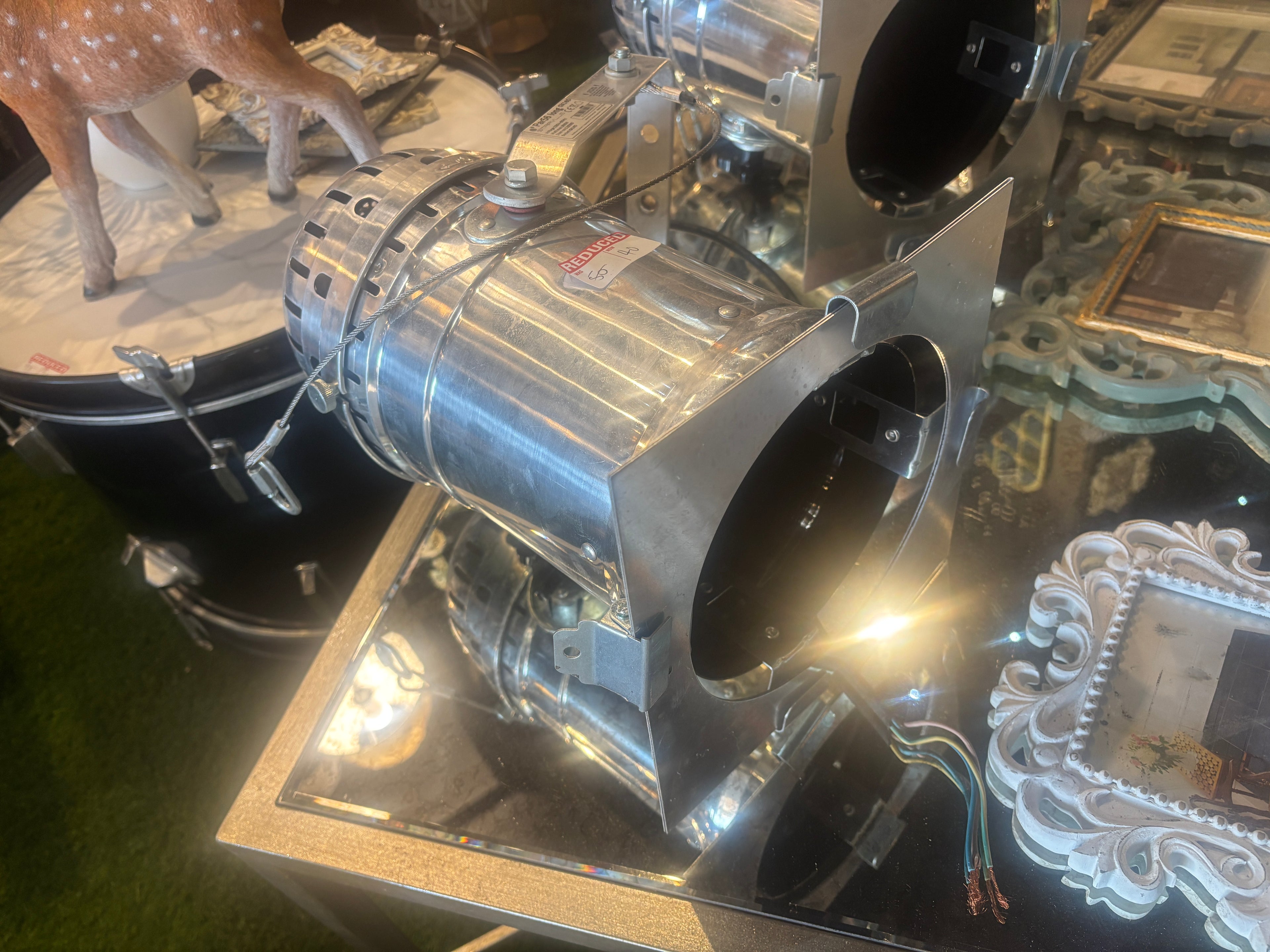 Metallic engine or mechanical component studio style spotlight on a reflective surface with decorative items in the background