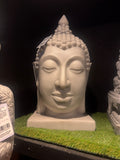 White stone Buddha head sculpture on a dark background