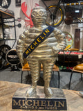 Metallic hand sculpture with Michelin branding on a wooden surface.