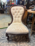 Decorative chair with tufted seat and wooden frame on a patterned floor.
